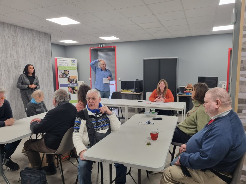 Photo de groupe: table du fond: Paul-andré anime le jeu entouré de Souad et Delphine. Les participants à leurs tables respectives écoutent attentivement.
