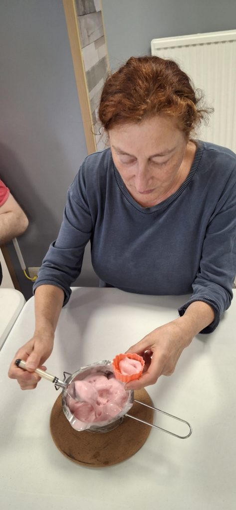 Pascale met le savon fondu dans les formes pour le faire sécher.